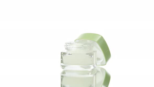 Skincare Cosmetic Glass Jar with Moisturizing Cream Rotating on White Background