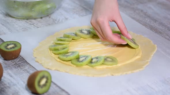 Female hands making galette with fresh kiwi