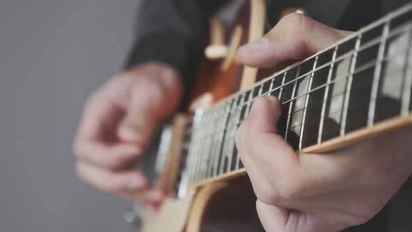 Man hands playing electric guitar pulling and pushing strings close up view. Music industry concept