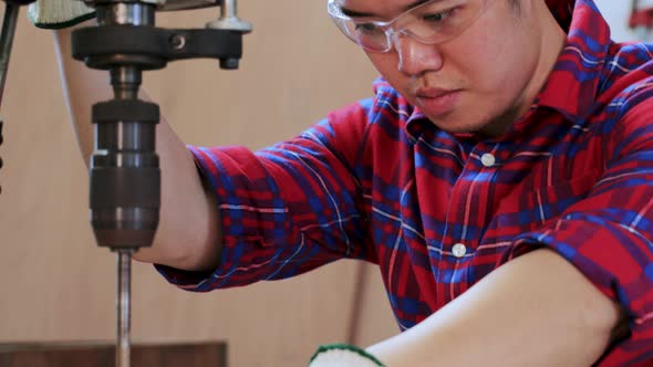 Close up of Carpenter drilling wood by drilling  machine in workshop factory