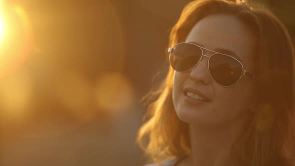 Lovely Girl Wearing Sunglasses, Smiling at Camera and Winking