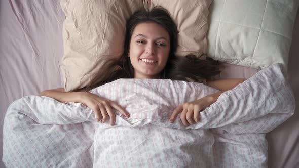 Top View of a Young Attractive Woman Stretching Hands While Lying in Bed in the Morning