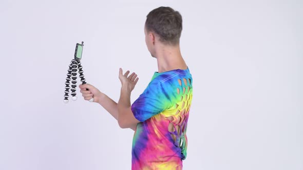 Studio Shot of Man Wearing Tie-dye Shirt and Vlogging with Phone