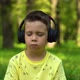 Boy listening to music sitting on the grass in the park - VideoHive Item for Sale