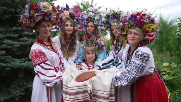 Gorgeous Ukrainian Young Women and Cute Little Girl Stretching Bread on Towel Looking at Camera