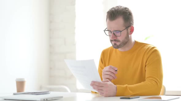 Man Reading Documents While Sitting in Office