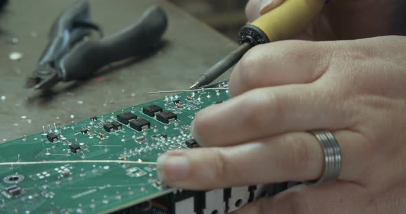 Worker inspecting and soldering electronic boards