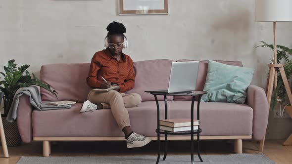 African American Woman Watching Online Lesson and Taking Notes