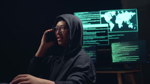 Asian Boy Hacker Using Computer Hacking And Talking On Phone