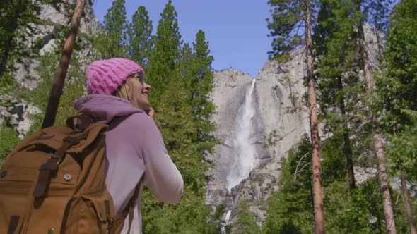 Slow Motion Young Traveler Woman Hiking in Forest with Yosemite Waterfall View