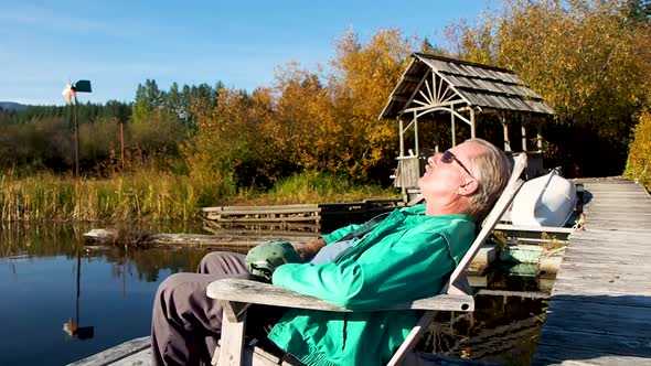 man sitting on dock at sunset