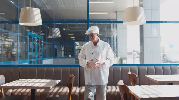 Portrait of Senior Chef in White Uniform Walking in Empty Cafe Waiting for Customers