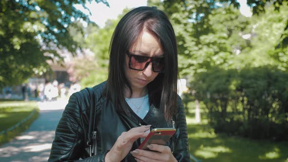 Woman Searching Information on a Smart Phone on the City Street. Technology and Lifestyle Concept.