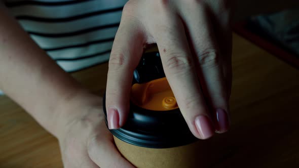 A Woman's Hand with a Pose Manicure on Her Fingers Occupies a Paper Cup with a Coffee Drink and