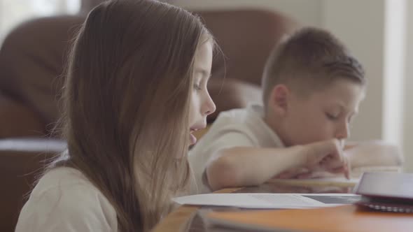 Close Up Portrait of Twin Sister and Her Tired Brother Twin Leafing Through Notebooks with Homework