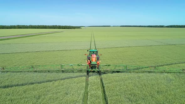 The Protection Of Plants.Tractor Spraying A Green Wheat Field