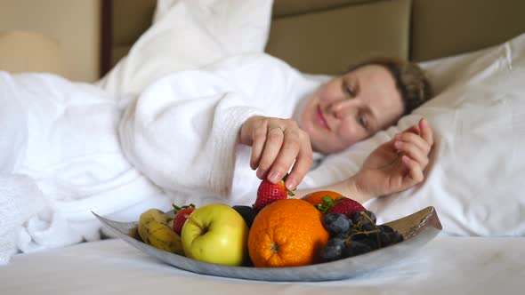 Young Woman Having Breakfast In Bed Enjoying Healthy Meal With Fruits