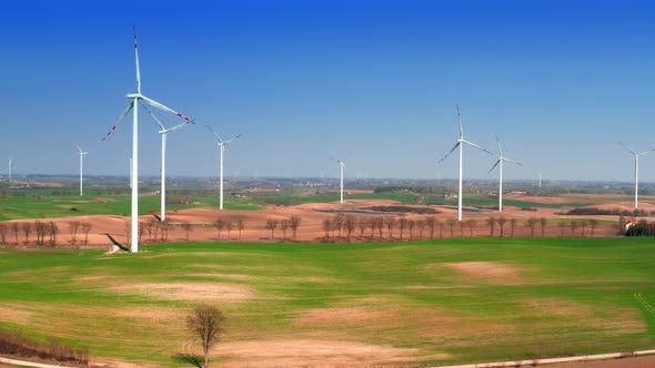 Farm of white wind turbines on spring field