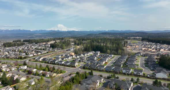 Wide aerial shot orbiting around Mount Rainier with neighborhoods underneath.