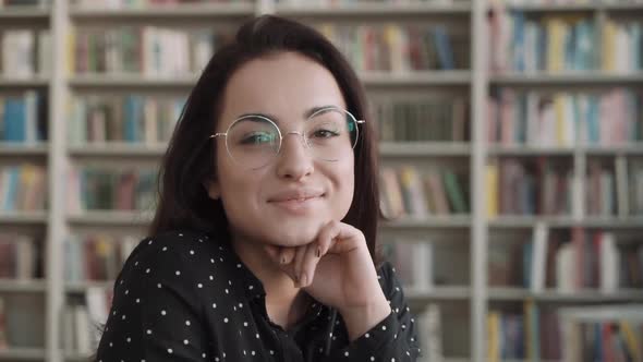 Portrait of Beautiful Young Woman Wearing Glasses Bookshelf on Background