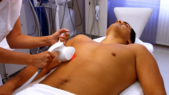Doctor performing laser hair removal on male patient
