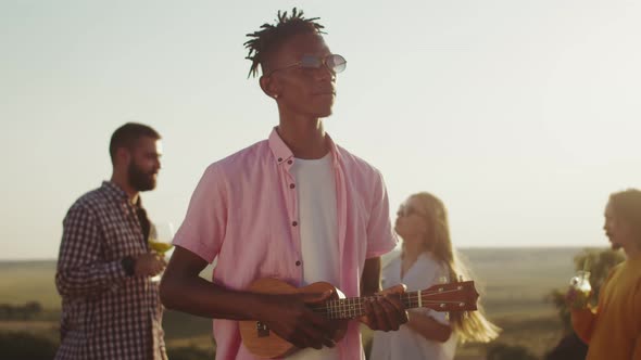 Happy Black Man Smiles Plays the Ukulele and Dances