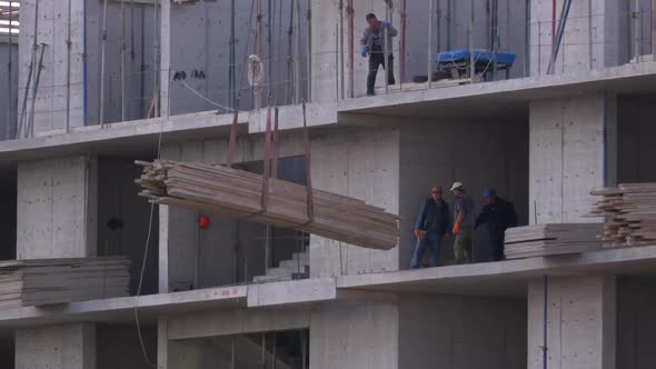 Builders at a Construction Site. Crane on a Construction Site Lifts a Load. Building Construction.