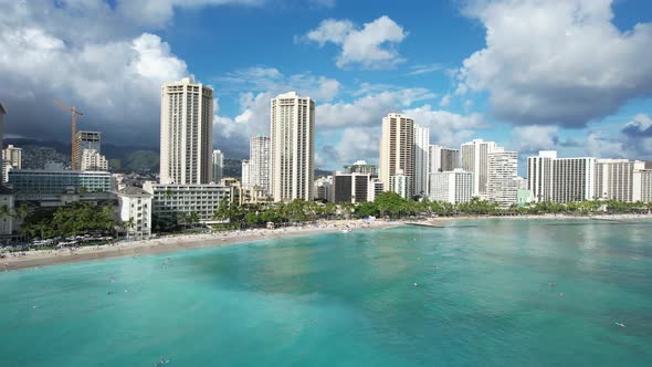 A drone glides over the ocean towards the beach revealing luxury ocean front hotels.