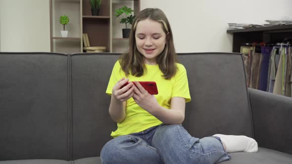 Happy Teen Girl Holding Cell Phone Using Smartphone Device at Home