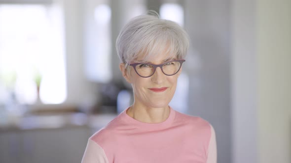 Slow motion portrait of an attractive happy mature senior woman smiling at home