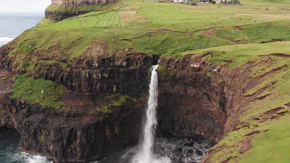 Stunning Waterfall Splashing From Cliff Aerial View. Mulafossur Waterfall Near Gasadalur Village at