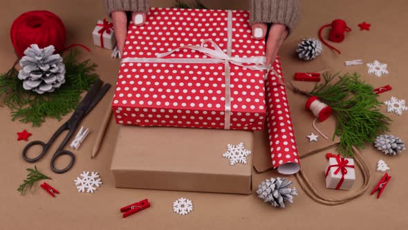 Woman packing Christmas gifts in red paper