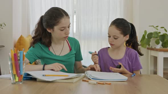 Teenage girl helping her young sister with homework during the COVID-19 pandemic