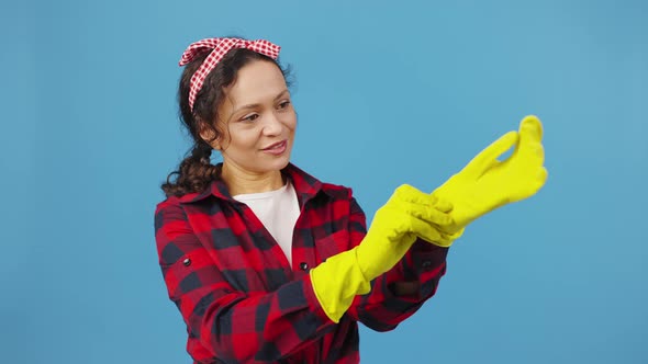 Cute Housewife Putting on Protective Rubber Gloves and Showing OK Gesture Smiling to Camera Blue