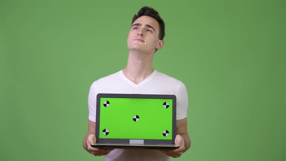 Young Handsome Man Thinking While Showing Laptop