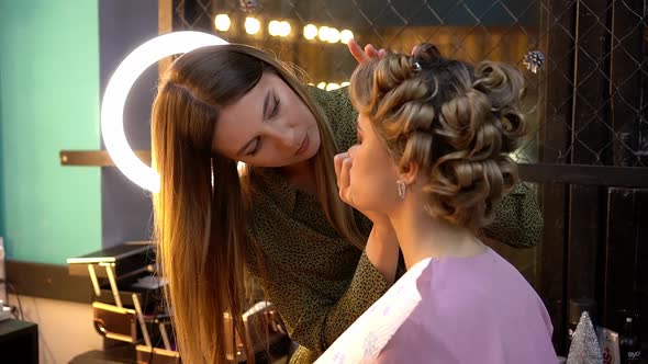 Professional Makeup Artist Applies Eye Shadow to Eyelid of Young Woman