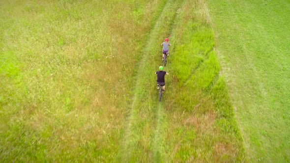 Aerial view of man and woman cycling in the forest on dirt road at Slovenia.