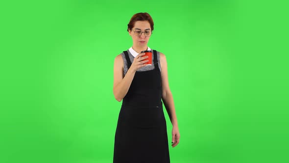 Funny Girl in Round Glasses Is Drinking Unpalatable Coffee with Red Paper Cup. Green Screen