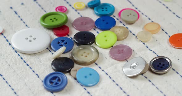 Colorful Buttons Falling on Striped Fabric Closeup