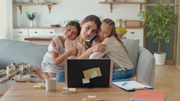 Lovely Mother Working Remotely From Home While Hugging Kids