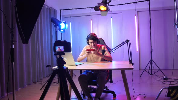 Excited Asian Man Playing Video Game With Mobile Phone While Live Stream With Light Equipment