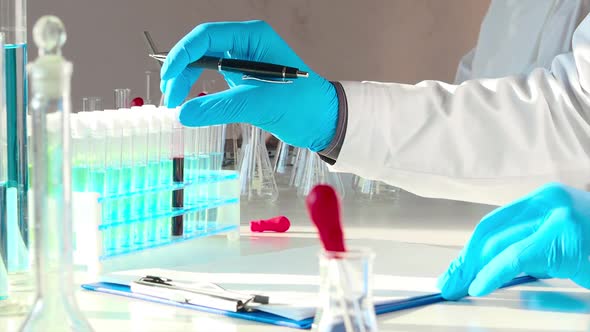 Modern Laboratory Research. Close Up Footage - Doctor Holds a Test Tube with a Blood Sample and Make alt