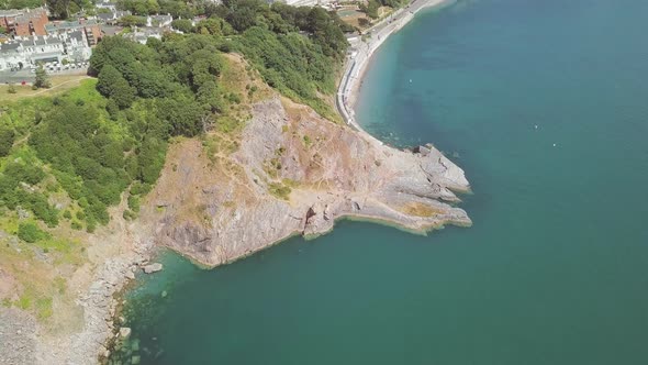 Zooming out with the drone over the landscape of Torquay. The beach and cliffs are visible below. Bu