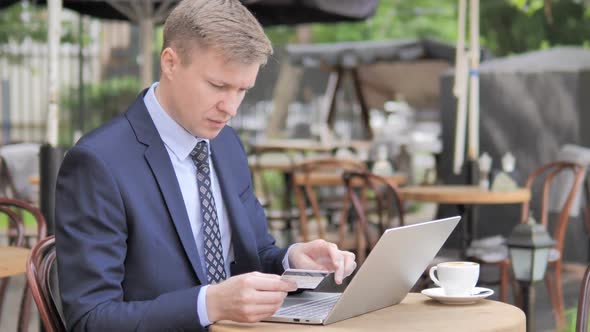 Online Shopping Failure for Businessman Sitting in Cafe Terrace