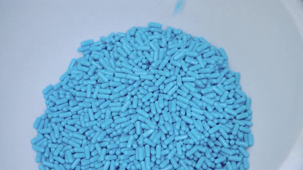 Produced Blue Capsules Falling Down to the Container