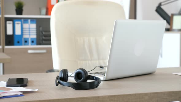 Empty Modern Office with a Desk in the Front and a Pair of Headphones Lying on the Table