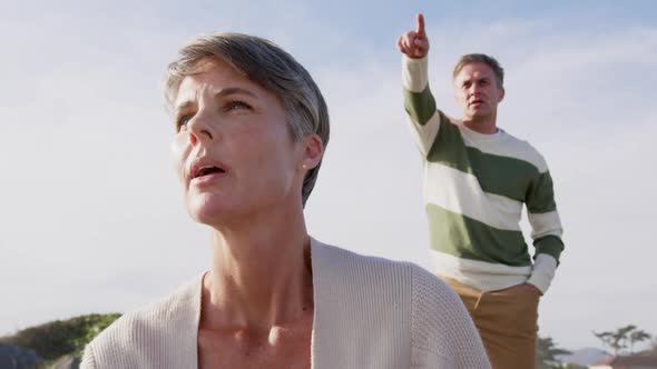 Caucasian couple enjoying free time by sea on sunny day looking away