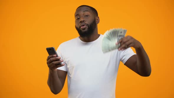 Excited Afro-American Man Holding Smartphone and Dollars, Online Money Transfer