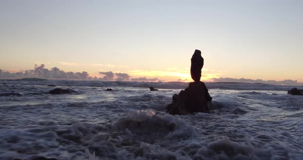 Stunning view of the sunset at low tide in Laguna Beach as the sun peaks out amongst rocks and refle