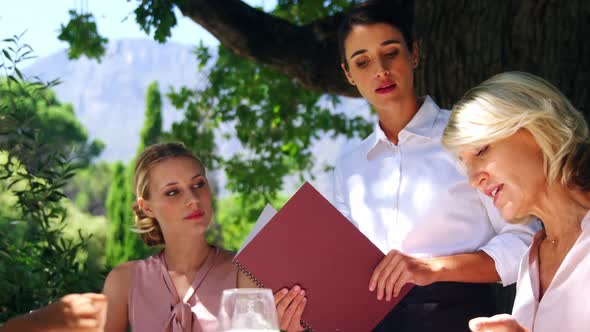 Waitress assisting customer while selecting menu